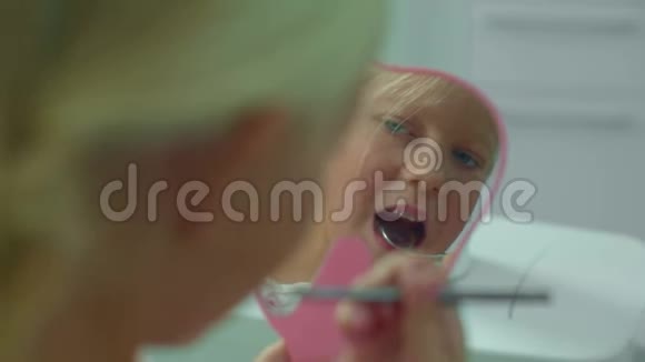 小女孩在镜子里看着她的牙齿视频的预览图