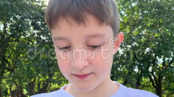 一个十几岁的白种人小男孩坐在夏季城市公园里用纸巾擦嘴用毛巾擦嘴吃过饭后闭上视频的预览图