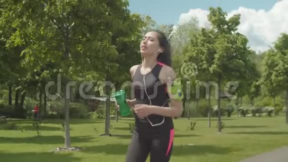 戴耳机的运动女人跑步时喝酒视频的预览图