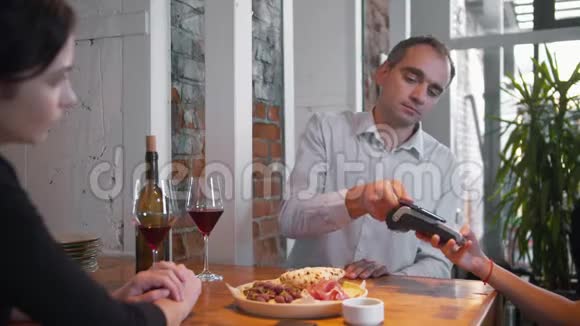 夫妻在浪漫的晚餐上一个男人通过电话支付食物视频的预览图