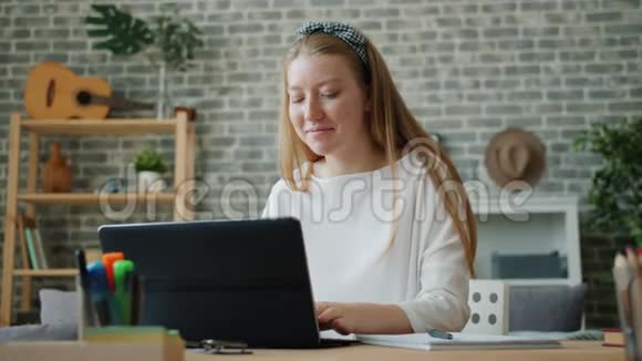 快乐的少女在家里使用笔记本电脑微笑然后在笔记本上做笔记视频的预览图