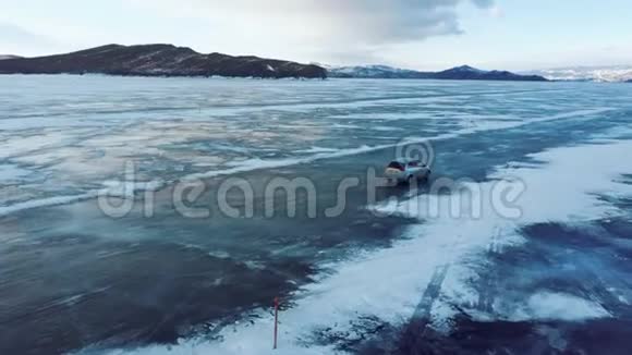 冬天汽车在贝加尔湖的蓝色冰层上行驶四翼飞机侧面的跟踪视图视频的预览图