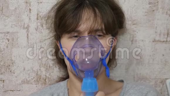 一个戴口罩的生病女孩吸入一个喷雾瓶戴蓝色医院面具的女人吸入呼吸道的蒸气视频的预览图