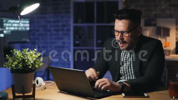 疲惫的上班族使用笔记本电脑打哈欠晚上在办公室工作的画像视频的预览图