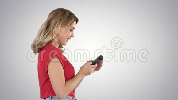 快乐可爱美丽的年轻女人在梯度背景下通过手机玩游戏视频的预览图