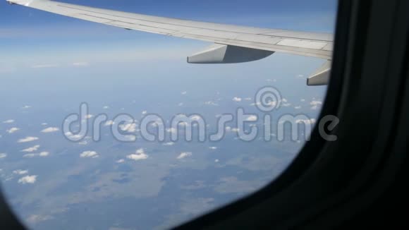 飞机飞过罕见的蓬松云从飞机机翼上的舷窗可以看到欧洲的田野视频的预览图