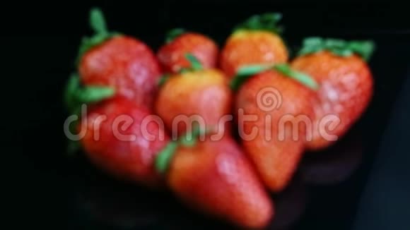 在黑色镜面上的整个成熟的红草莓群中的俯视焦点视频的预览图