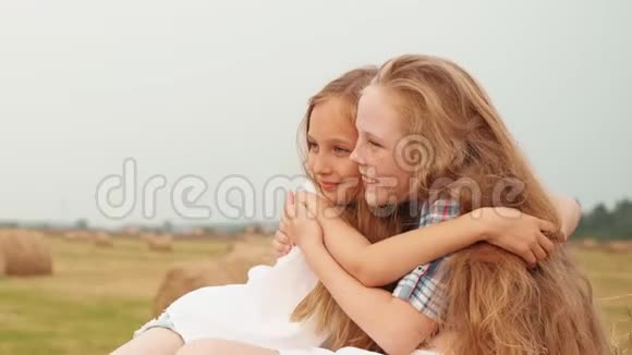 在乡村度假的收获场上嬉戏的女孩拥抱在干草堆上微笑的女朋友拥抱大海视频的预览图