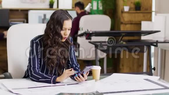 白种人年轻的女建筑师在她的手机上检查笔记视频的预览图