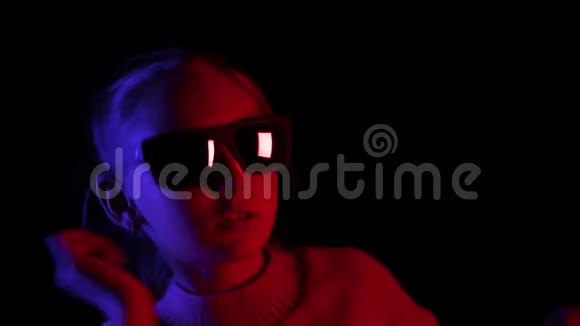 年轻女孩戴着深色太阳镜在黑色背景上用蓝色和红色照明跳舞一位著名的舞女视频的预览图
