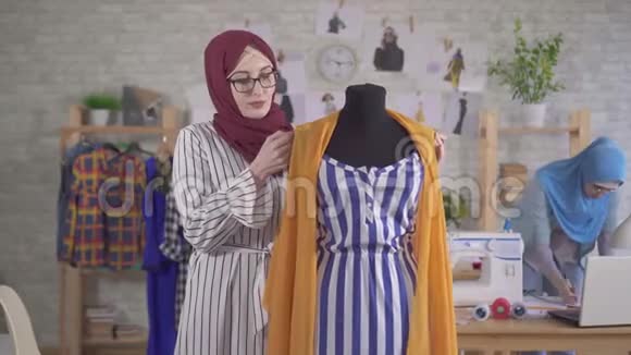 国家头巾上的年轻穆斯林女时装设计师用卷尺测量视频的预览图