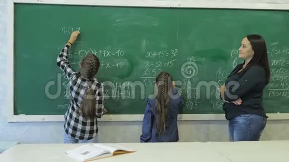 小学小女生在教室的绿色粉笔板上写数字视频的预览图
