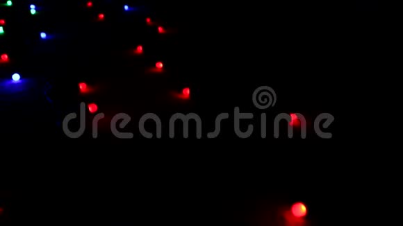 在闪烁的多色明亮的灯光下一个花环躺在黑暗的地板上视频的预览图