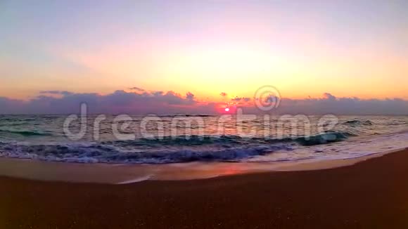 海浪拍打在沙滩上令人难以置信的橙色温暖的黄昏日落在海滨景观稳定的视野视频的预览图