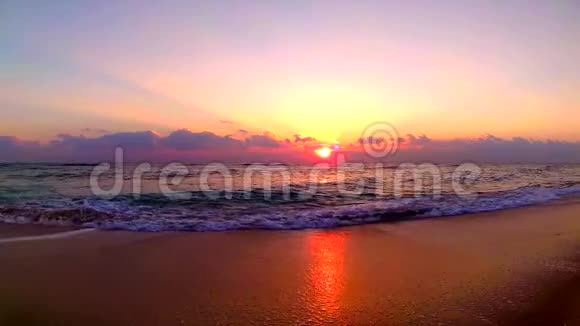 海浪拍打在沙滩上在美丽的橙色温暖的黄昏日落在海边的风景稳定的视野视频的预览图