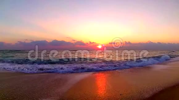 海浪拍打在沙滩上美丽的橙色温暖的黄昏日落在海滨景观稳定的视野视频的预览图