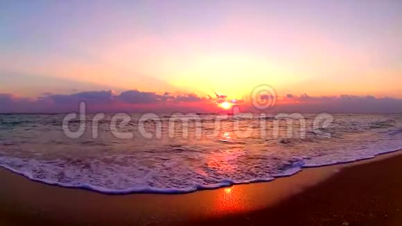 海浪拍打在沙滩上在美丽的橙色温暖的黄昏日落在海滨景观稳定的视野视频的预览图