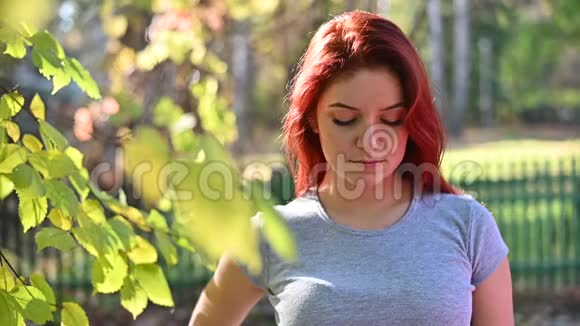 美丽悲伤的红发女人独自走在森林里穿着灰色T恤和条纹裤腿的女汉子走进来视频的预览图