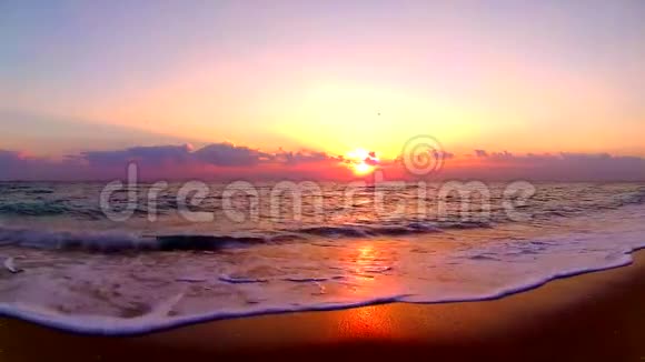 海浪拍打在沙滩上美丽的橙色温暖的黄昏日落在海边的风景稳定地观看视频的预览图