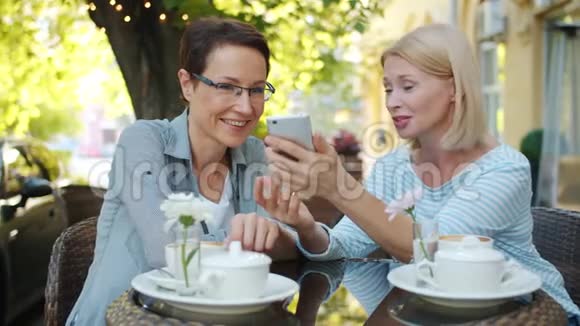 漂亮的成熟女人用智能手机谈笑风生视频的预览图