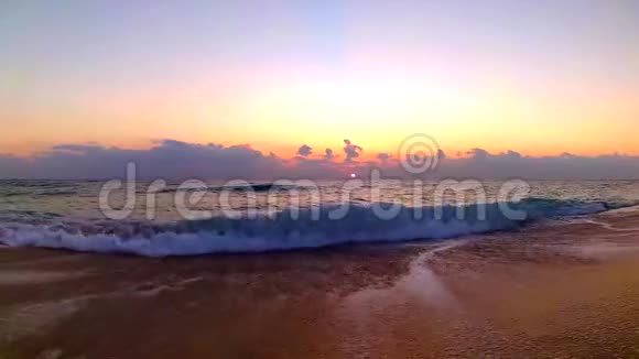 海浪拍打在沙滩上迷人的橙色温暖的黄昏日落在海滨景观稳定的视野视频的预览图