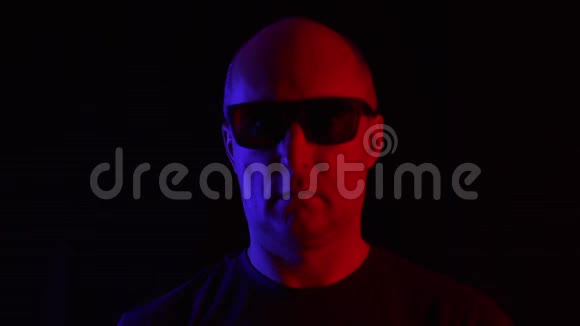 一个戴墨镜的秃头男人黑底蓝红相间黑工作室中戴墨镜的成人肖像视频的预览图