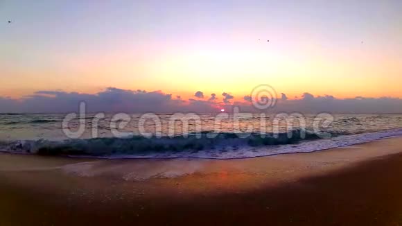 海浪拍打在沙滩上壮丽的橙色温暖的黄昏日落在海滨景观稳定的视野视频的预览图