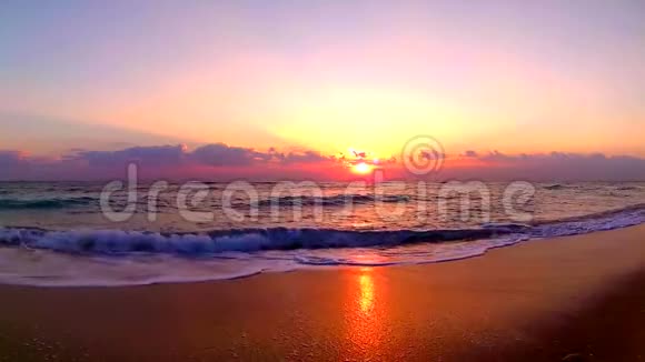 海浪拍打在沙滩上在美丽的橙色温暖的傍晚日落在海滨景观稳定的视野视频的预览图