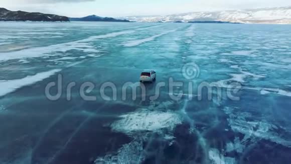 冬天汽车在贝加尔湖的蓝色冰层上行驶从四翼飞机后面的跟踪视图视频的预览图