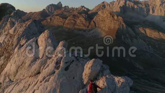 在美丽的日落中一个人在山的边缘徒步旅行的空中史诗镜头视频的预览图