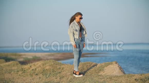 穿牛仔裤的女孩在海边视频的预览图