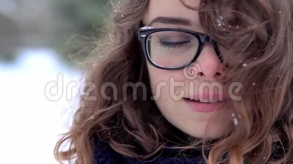 戴着眼镜的漂亮女人的特写脸享受着她头发上的雪和风视频的预览图