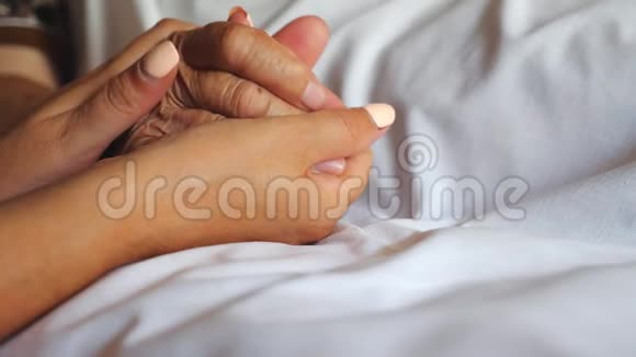 无法辨认的女人牵着她的老母亲躺在床上表现出关怀或爱女儿温柔动人视频的预览图