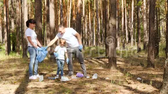 幸福家庭在森林里收集垃圾爸爸和儿子把垃圾放进袋子里父母抚养孩子视频的预览图