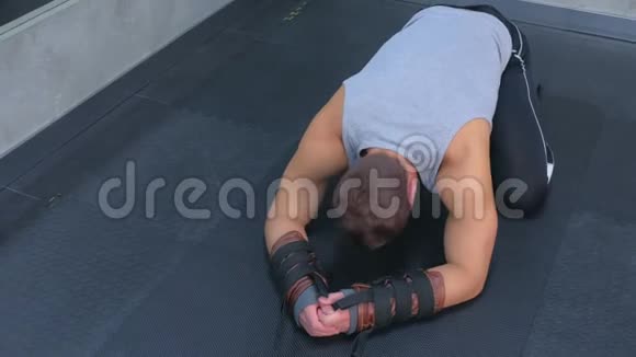 运动员躺在垫子上准备使用教练为肌筋膜伸展健身房视频的预览图