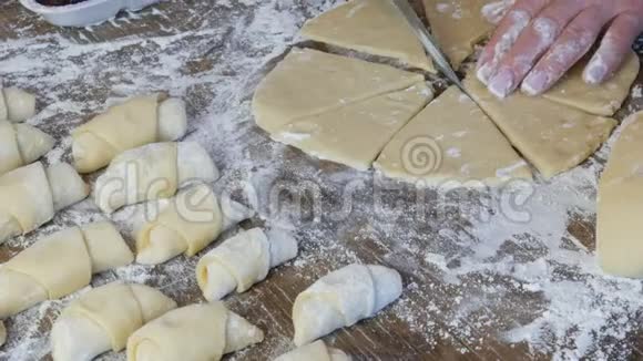 一个面包师的女手在厨房里用一把薄刀切面团自制新鲜美味的糕点小面包和视频的预览图