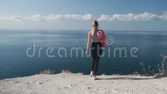 后景穿着运动服的女人走到悬崖边张开双臂视频的预览图