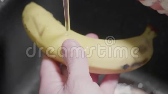 人用洗涤供应商和海绵清洗香蕉泡沫在手上和香蕉上黑色水槽在背景上关门视频的预览图