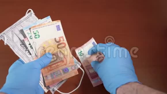 带着蓝色的医疗手套欧元钞票和带有冠状病毒字样的面罩视频的预览图