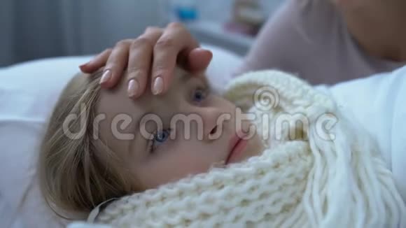 母亲安慰裹着围巾的小女儿躺在床上格里普和健康视频的预览图