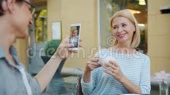 朋友在街咖拿着咖啡杯拍照美丽成熟的金发美女视频的预览图
