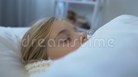 戴着围巾的小病女孩子躺在床上患有格里普病季节性疾病视频的预览图