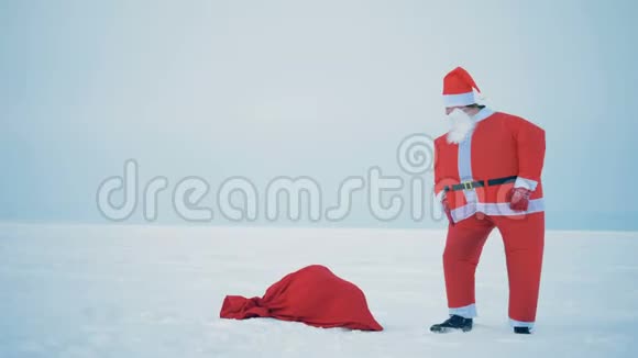 圣诞老人正拿着礼物在包旁边的雪地里跳视频的预览图