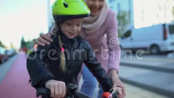 妈妈帮助骑自行车小女儿支持孩子运动和爱好视频的预览图