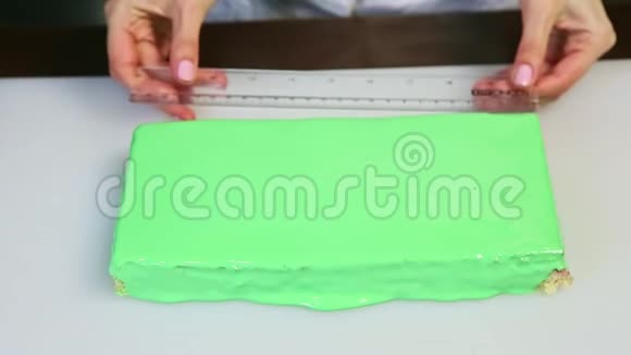厨师制服的糖果师把尺子放在绿色釉面矩形分层蛋糕旁边视频的预览图
