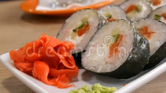 大寿司卷在诺里与鲑鱼蟹棒黄瓜费城奶酪附近有绿色的芥末和红色视频的预览图