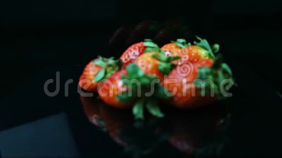 把注意力集中在一堆新鲜多汁的红色草莓上放在黑色的背景上视频的预览图
