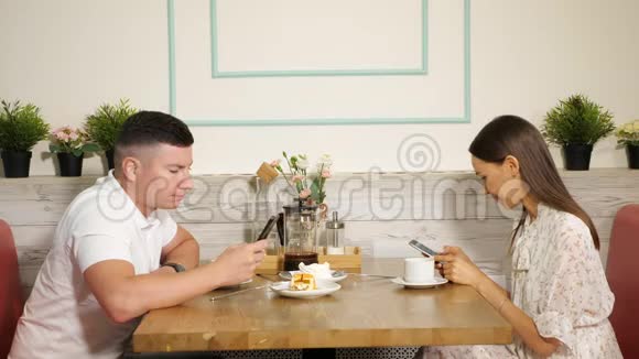 男人和女人在餐桌上用电话在咖啡馆里用甜点视频的预览图