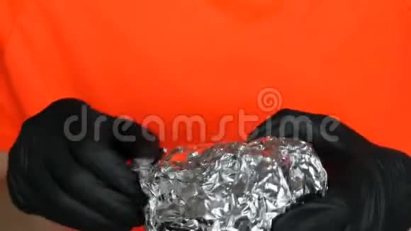 一个少年展开大箔汉堡双手戴专用黑色手套手拿垃圾食品快餐脸部和嘴巴靠近视频的预览图
