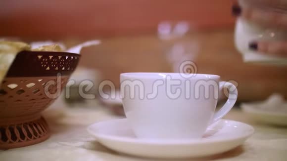 靠近女人的手拿着茶壶把热茶倒进前景上的白碗里饮茶仪式视频的预览图